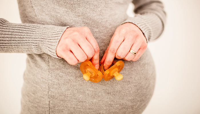 Pregnant woman holding two pacifiers