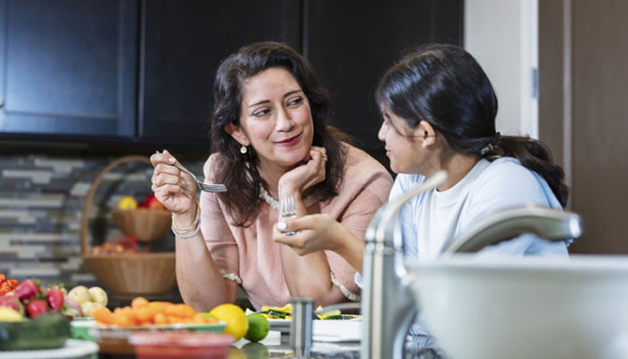 A mother and daughter eating vegetables