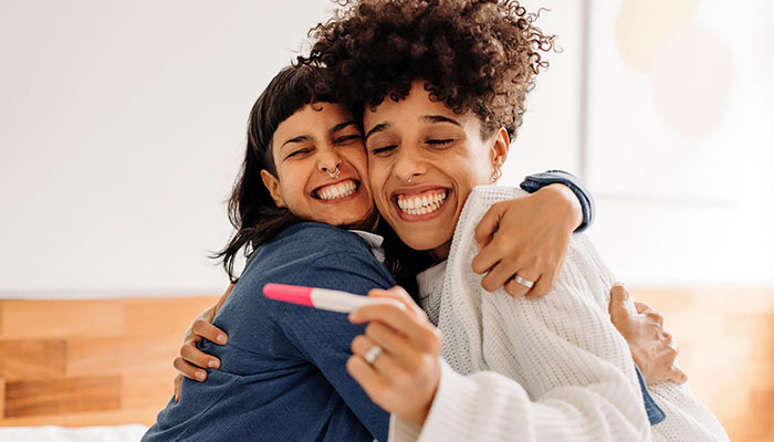 Female couple celebrating pregnancy test results