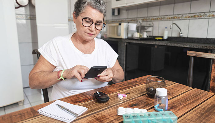 Woman reading diabetes glucometer at table