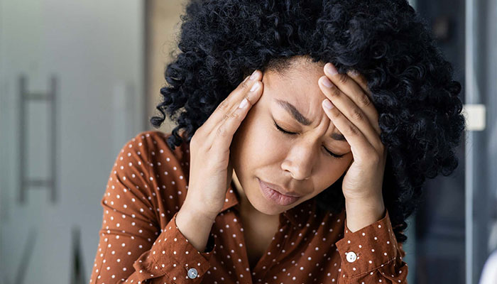 Woman holding her head and grimacing
