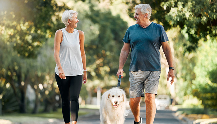 older couple walking outside with dog