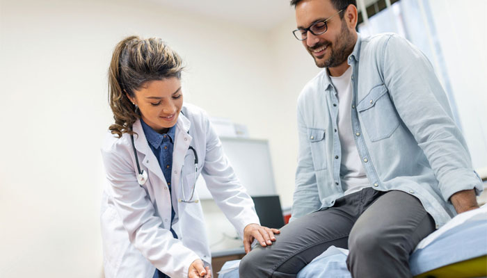 Provider examining a male patient in an exam room.
