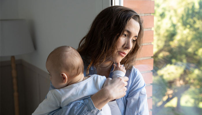 Woman with a sad expression holding a baby