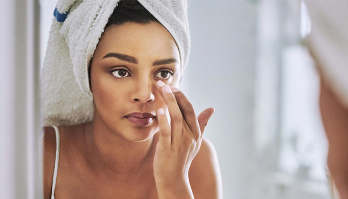 Woman applies moisturizer to her face after a shower to prevent dry skin in winter.