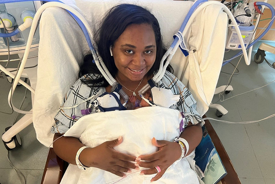 woman in hospital bed smiling while holding newborn twins