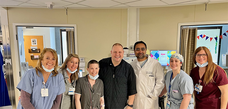 Patient post-surgery with doctor, medical staff, and her spouse standing and smiling in the hospital