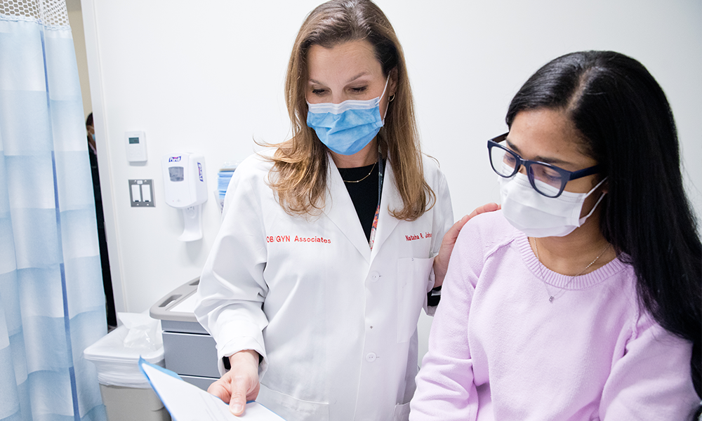 female doctor with female patient in exam room reviewing form