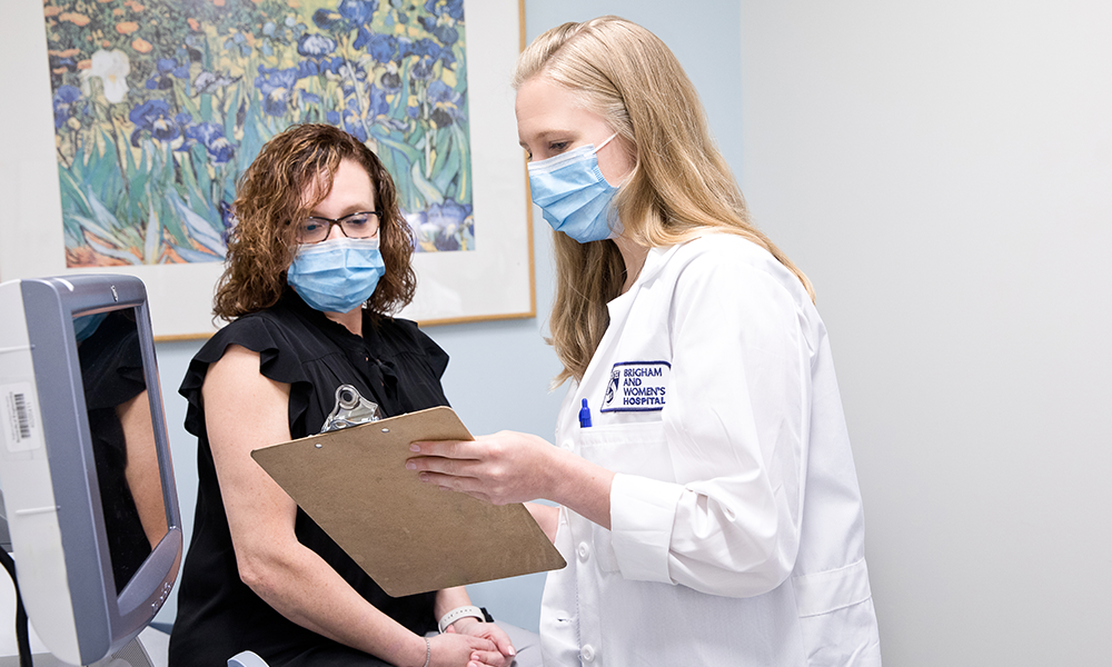female clinician reviewing chart with female patient in exam room