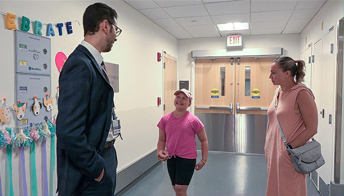 Celeste Pardo stands in a hallways with her doctor and mother