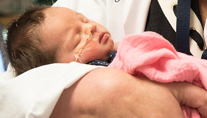 doctor holding baby in NICU